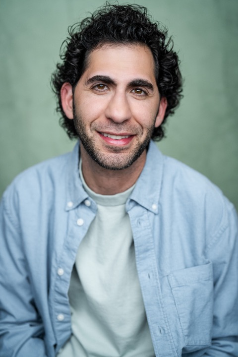 Luca Cundo smiling in a light blue shirt against a green backdrop
