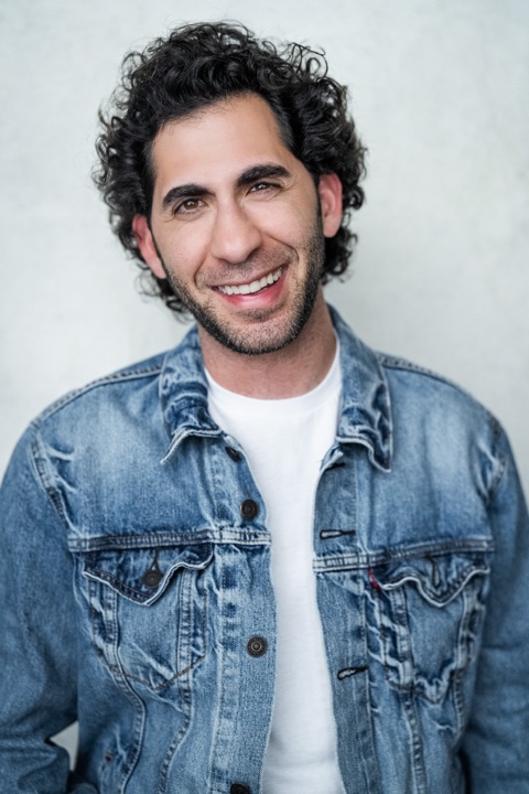 Luca Cundo laughing in a denim jacket and white t-shirt
