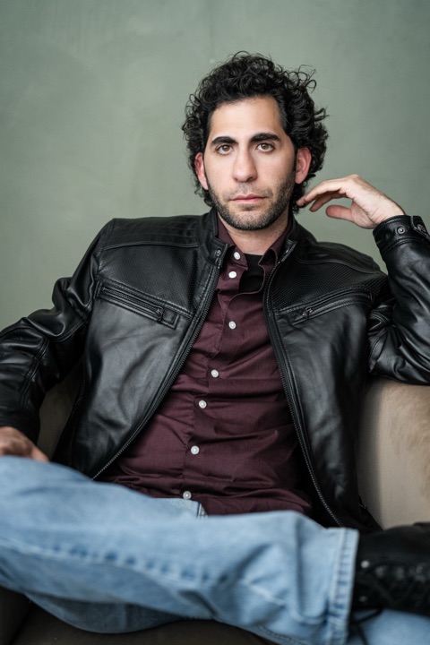 Luca Cundo seated in a leather jacket and jeans