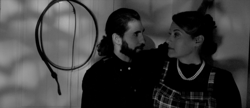 Luca Cundo as Peter in Killing Hope, beside a woman in pearls, in black and white